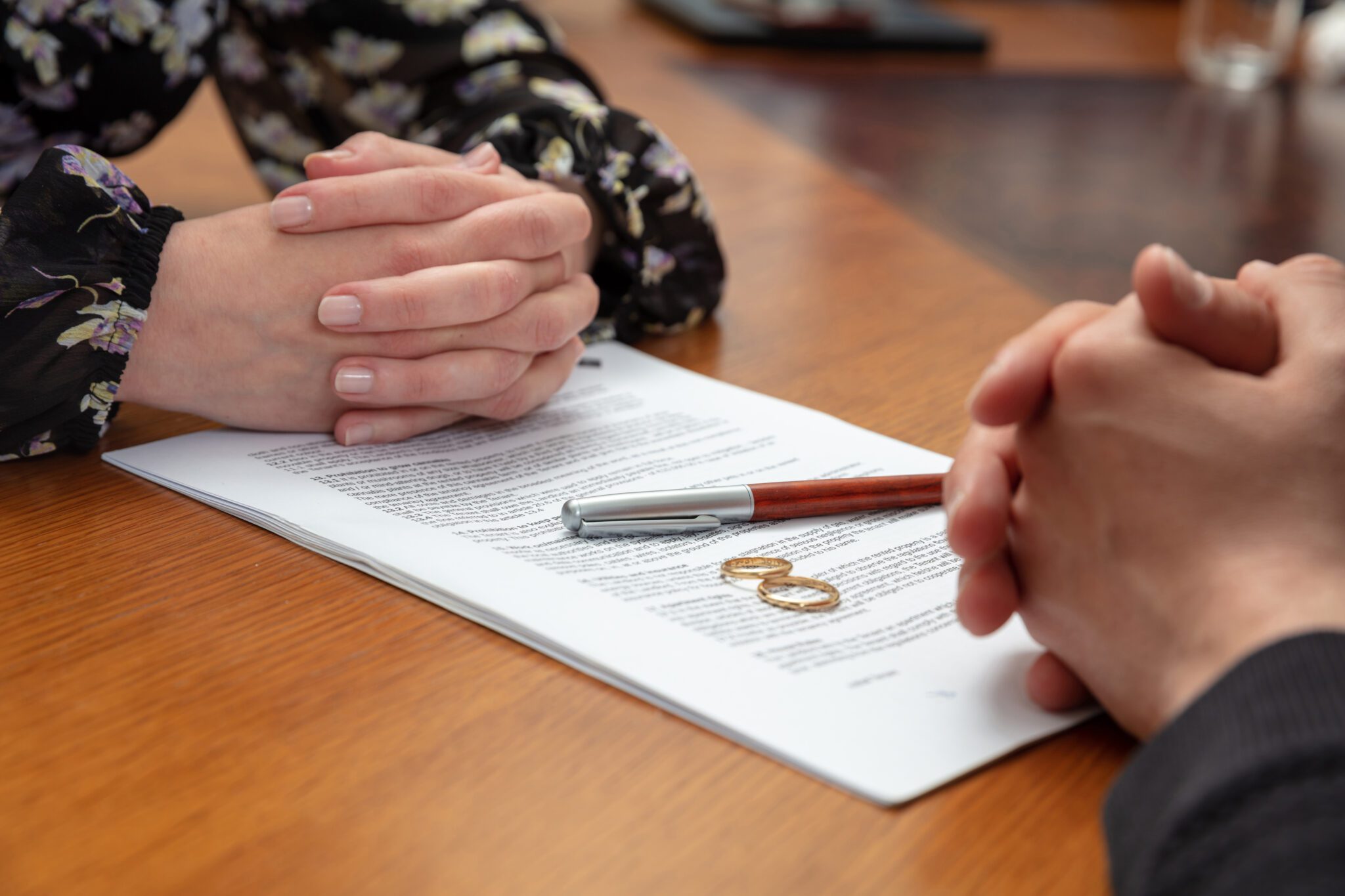 Two people with clasped hands reviewing a document on a table.