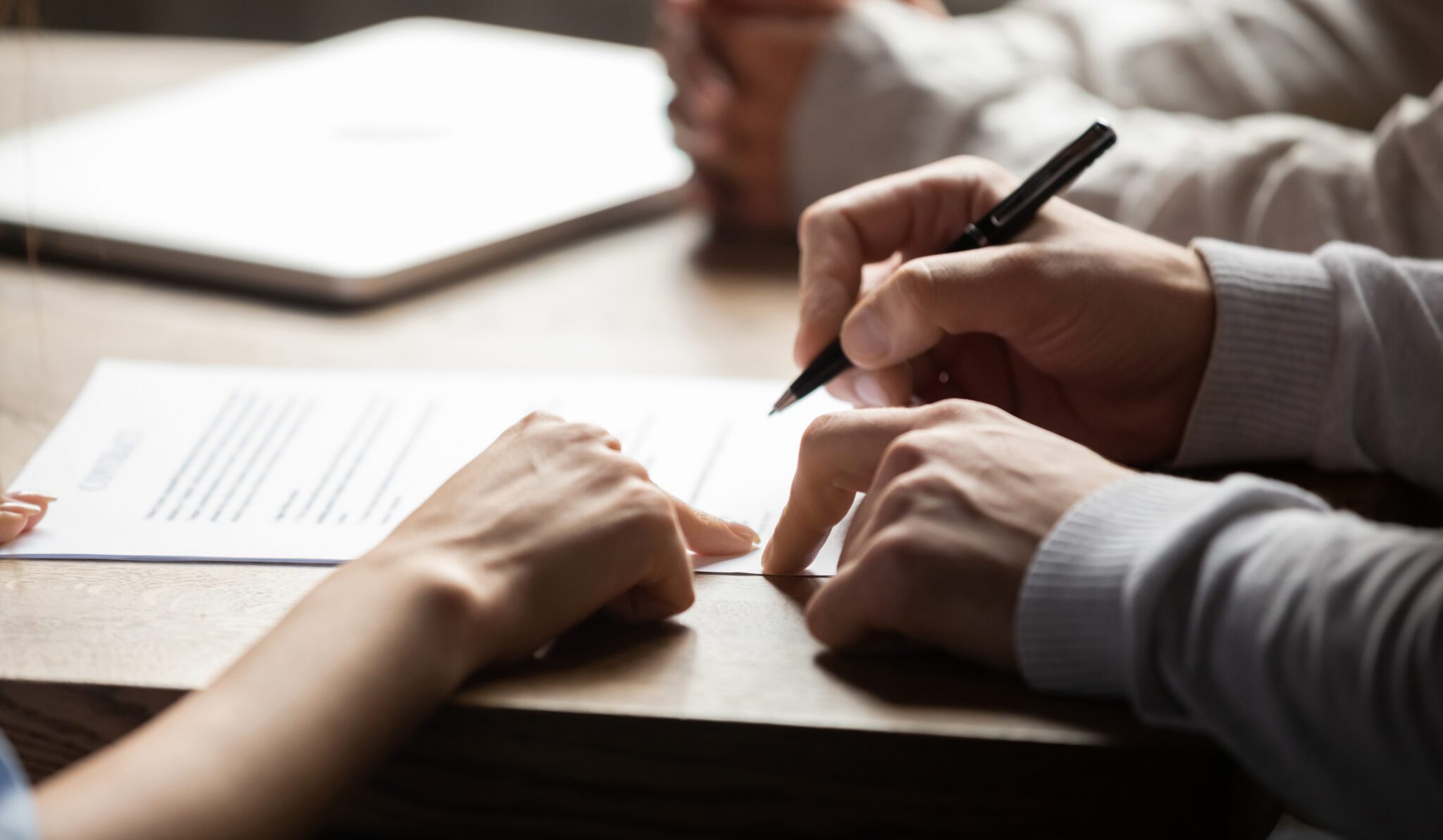 Close-up of hands signing a document on a table.