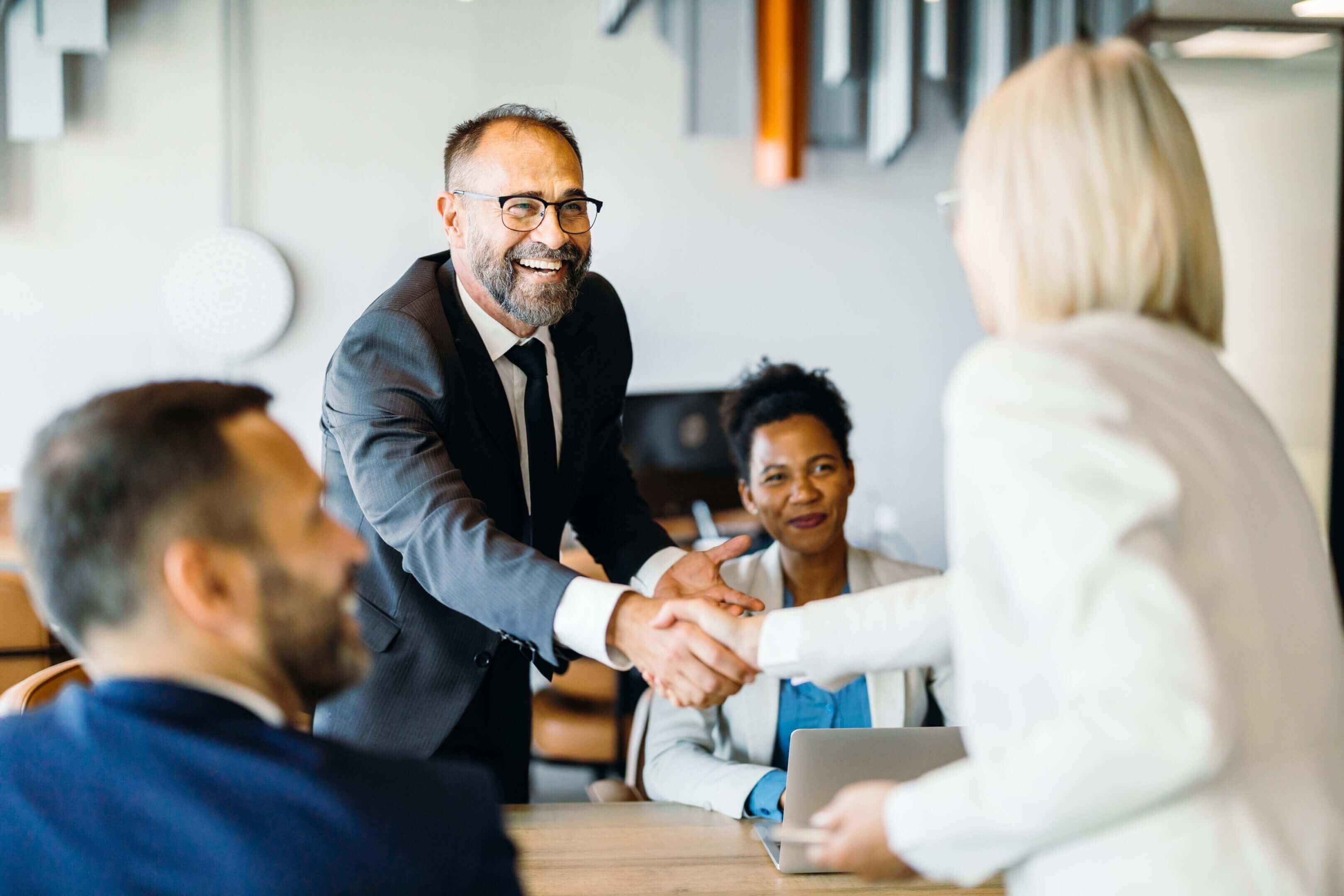Two business professionals shaking hands in a meeting.