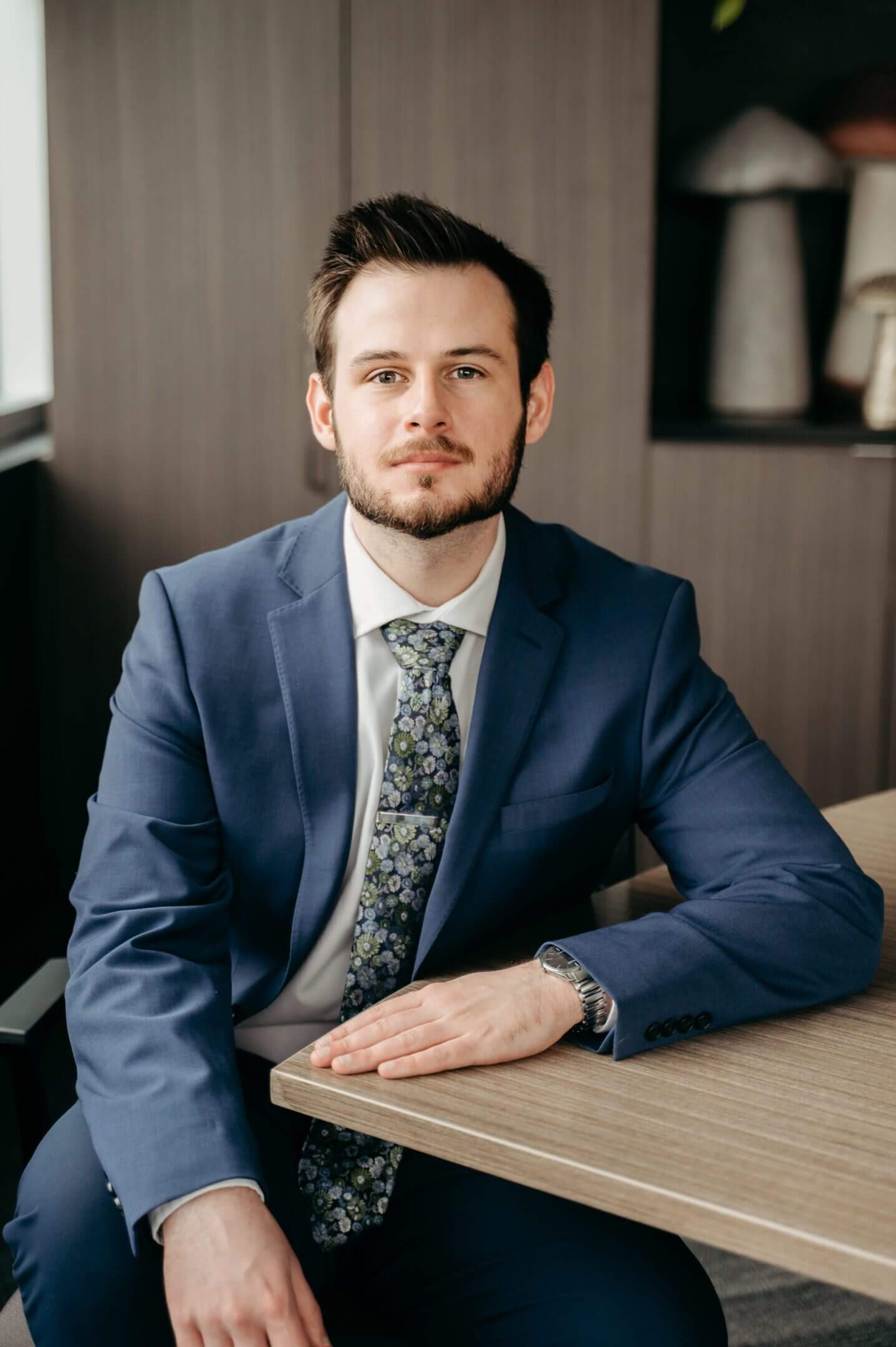 Man in blue suit sitting at desk.