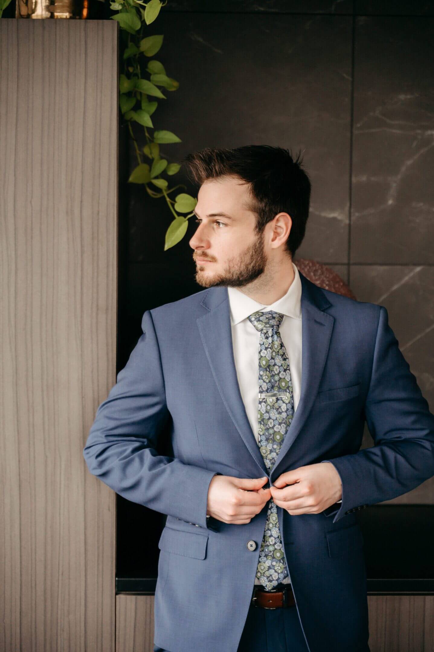 Man in blue suit adjusting his jacket.