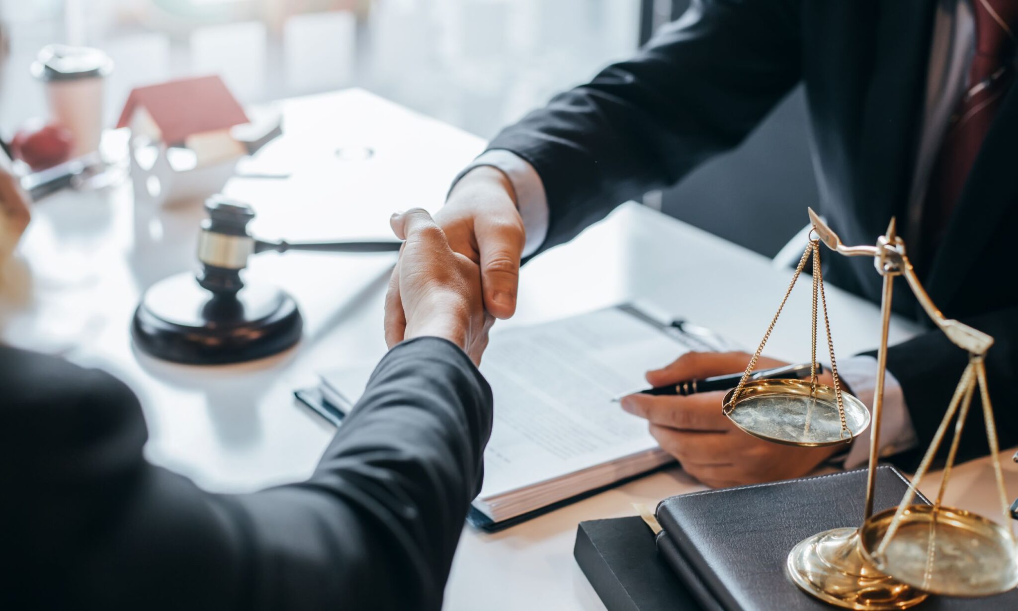 Handshake over legal documents and scales.