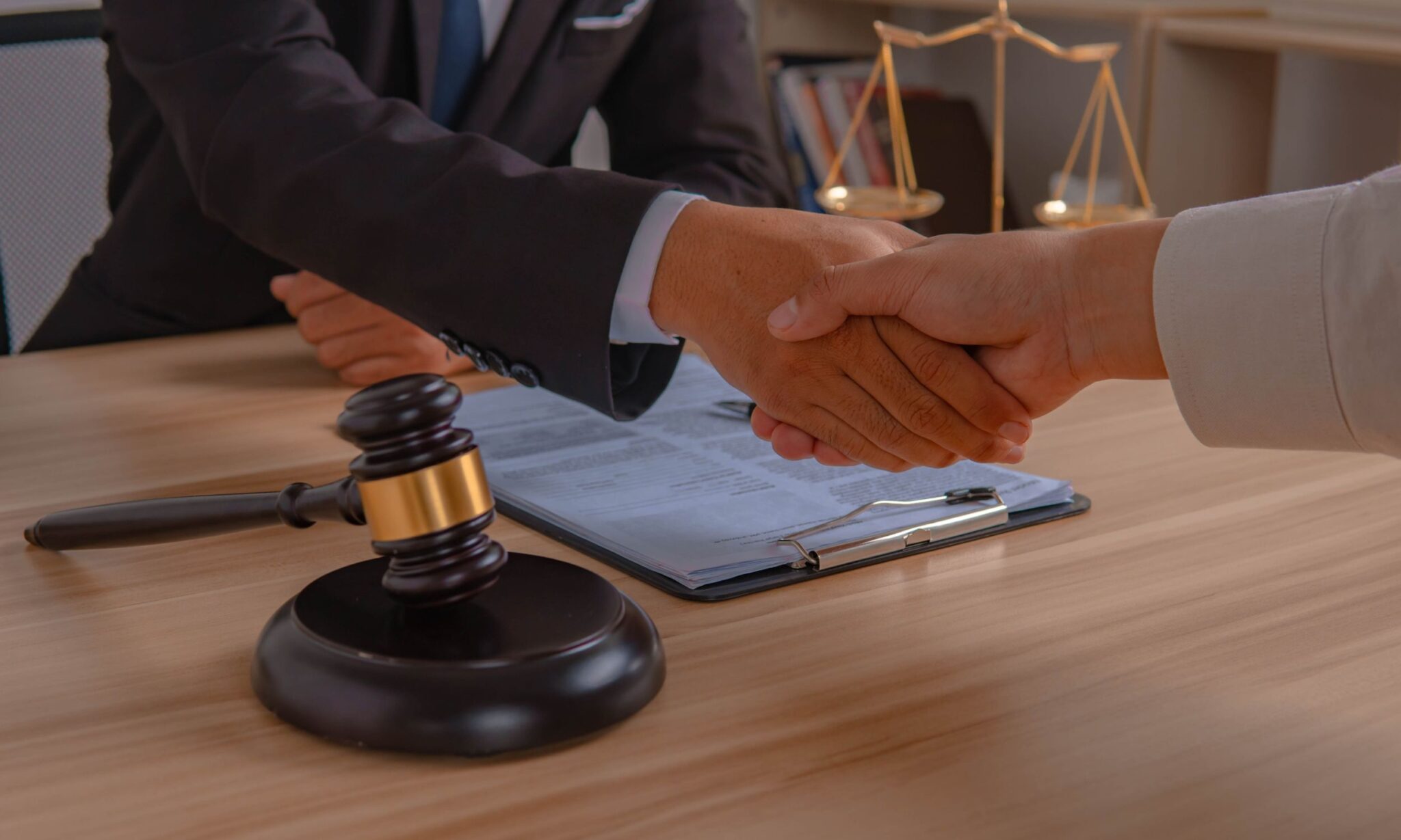 Handshake over legal documents and gavel.