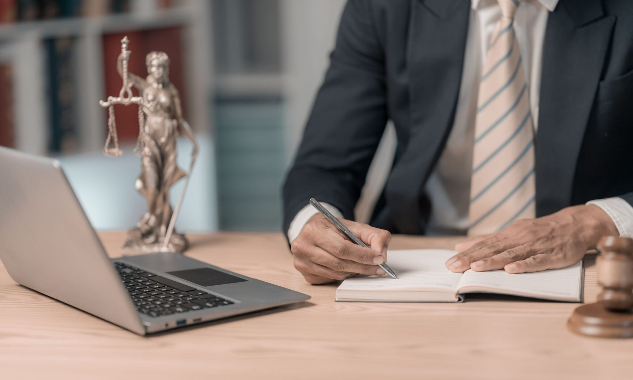 Lawyer writing at desk with laptop.