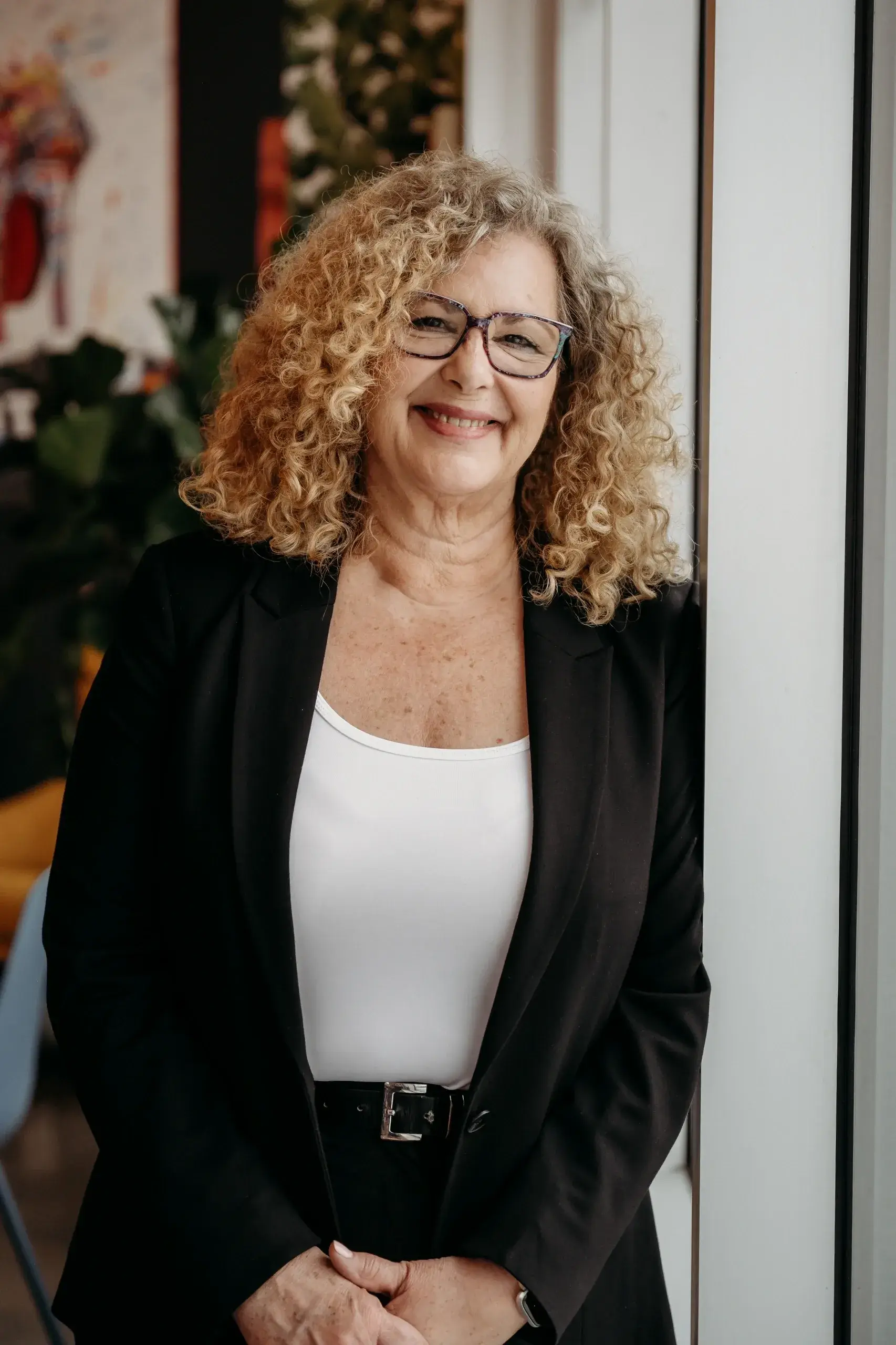 Smiling woman with curly hair and glasses.