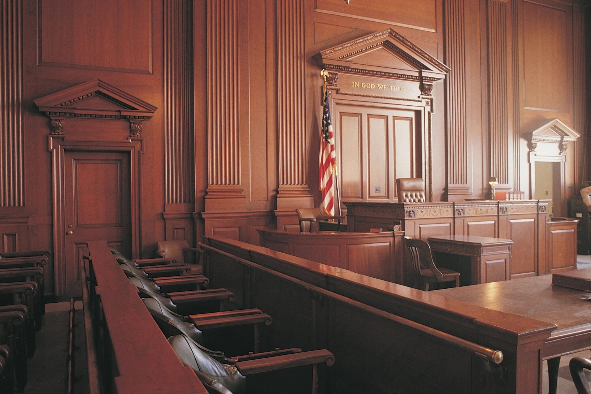 Empty courtroom with wooden interior and flag.