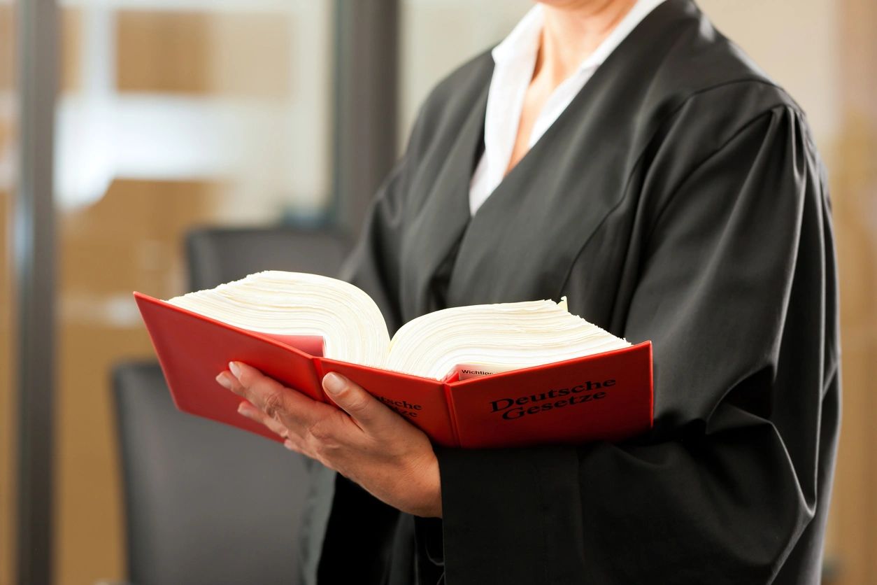 Person in robe holding an open book.