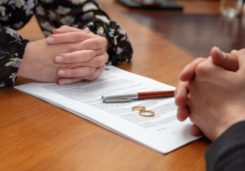 Two people with clasped hands reviewing a document on a table.