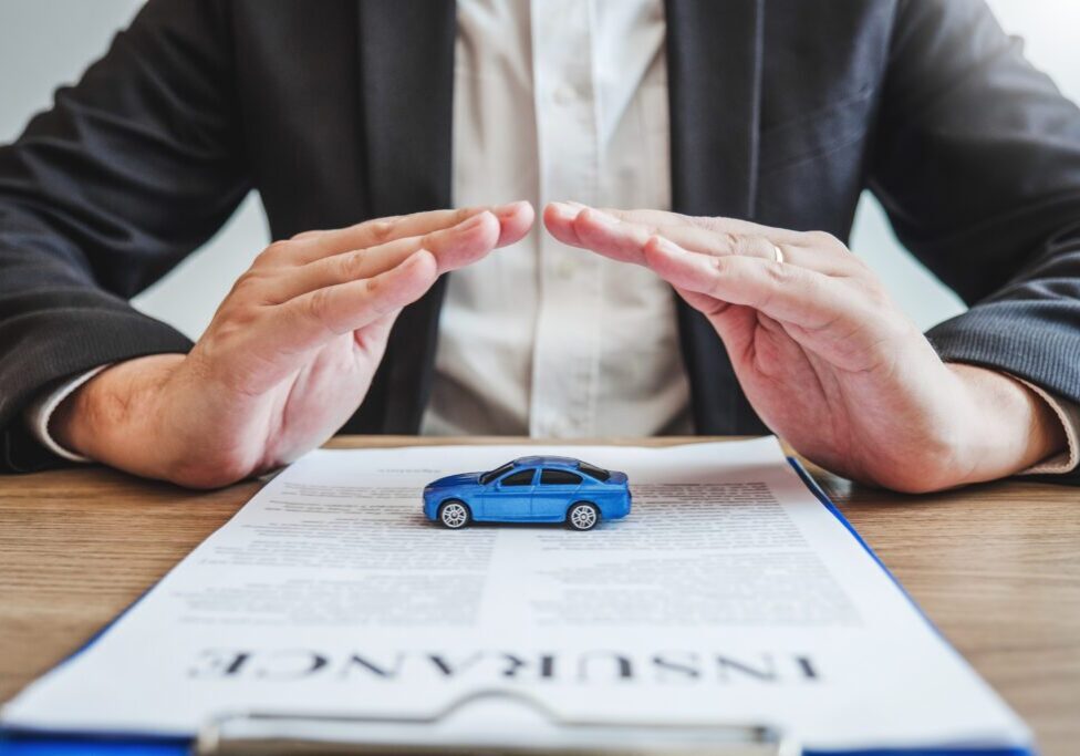 A person protecting a toy car on an insurance document.