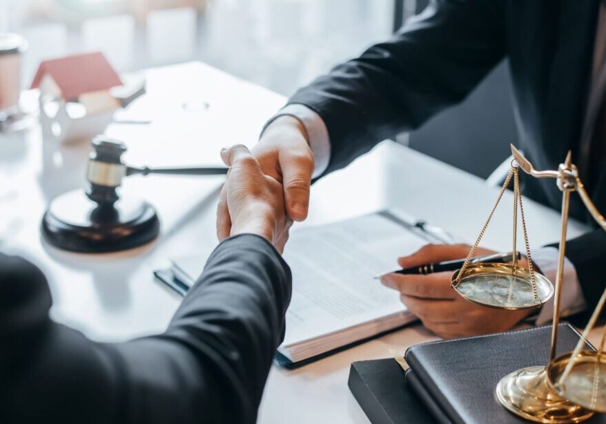 Handshake over legal documents and scales.