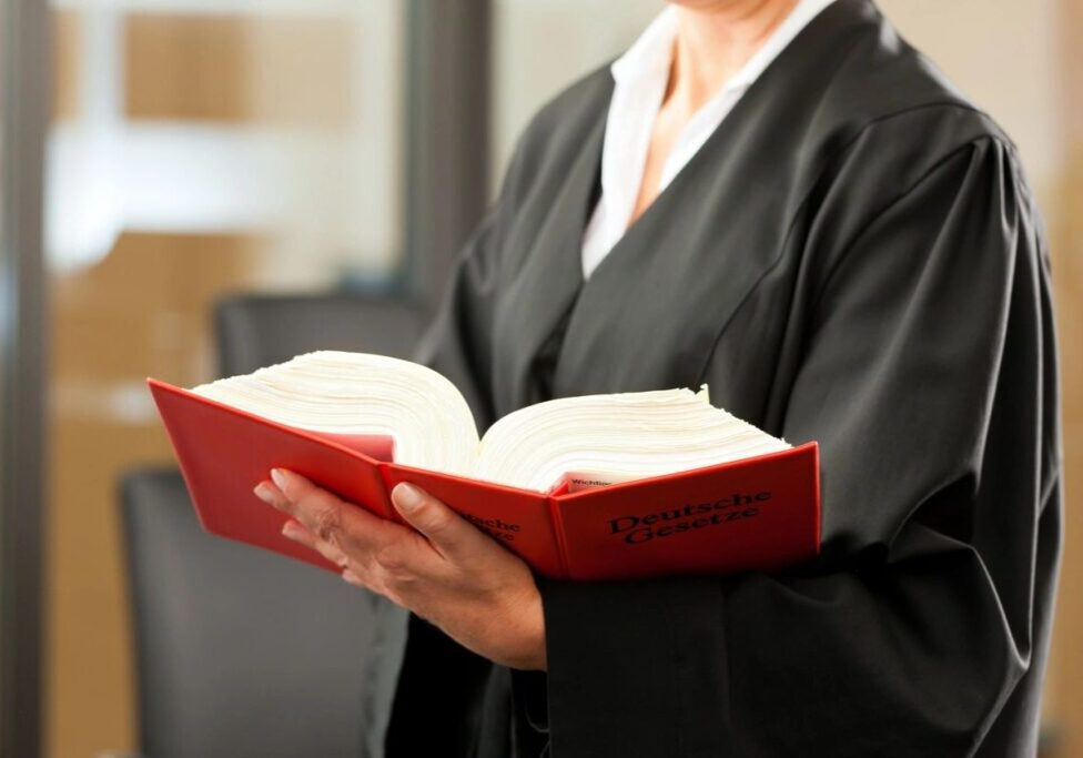 Person in robe holding an open book.