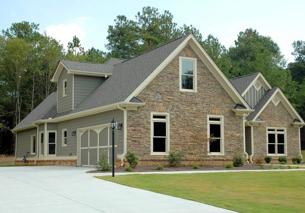 Modern stone house with large driveway.